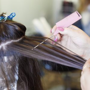 The hairdresser paints a brunette woman's hair in the beauty salon.